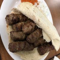 Cevapi · Traditional beef kebabs served on a traditional lepinja pita with a side of raw chopped onio...