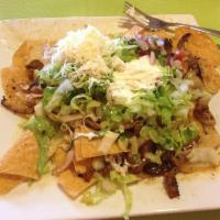 Fajita Nacho Salad · A bed of tortilla chips smothered with cheese sauce and topped with grilled strips of chicke...