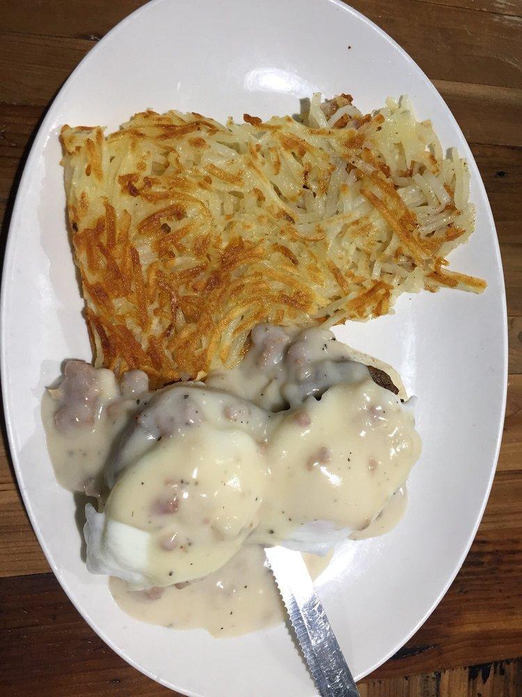 Southern Benedict Breakfast · A split buttermilk biscuit topped with sausage patties, poached eggs and creamy sausage gravy. Served with hash browns or grits.
