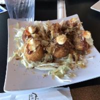 Takoyaki · Fried octopus dumplings drizzled with Japanese mayonnaise and katsu sauce and sprinkled with...