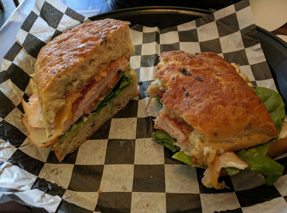 Turkey Focaccia · Smoked turkey breast and bacon with Gouda cheese, forest greens, tomato, and basil aioli.