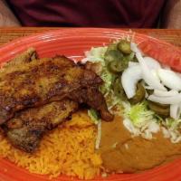 Carne Asada · Tender, grilled rib-eye steak served with fried beans, rice, lettuce, raw onions, tomatoes, ...