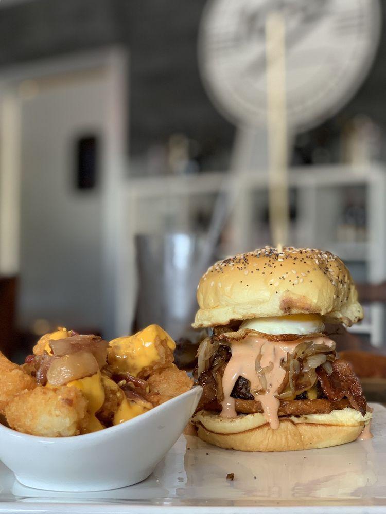 Wake Up Burger · Angus beef, aged cheddar cheese, applewood smoked bacon, hash brown patty, charred balsamic onions, baby pink sauce, and a fried egg to top it off. Served on a sesame bun.