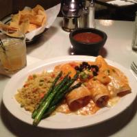 Enchiladas De Mariscos · Original blend of scallops, shrimp and crab meat rolled in a flour tortilla, topped with cho...