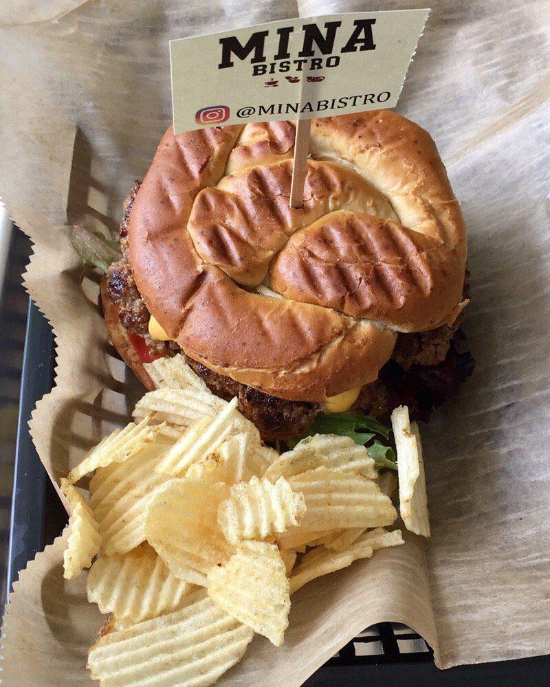 Premium Pretzel American Burger · Crispy bacon, American cheese, red onion, tomato, mixed greens, garlic sauce, cilantro sauce and pineapple sauce.