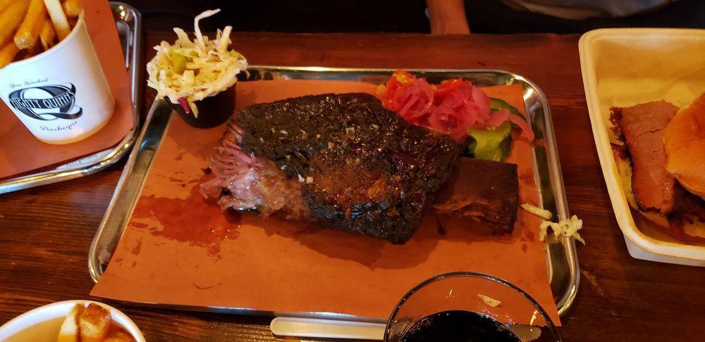 Brontosaurus Rib · On-the-bone, slow-smoked Short Rib with almost a full pound of meat on the rib. Served with an optional assortment of pickled veggies & slaw.