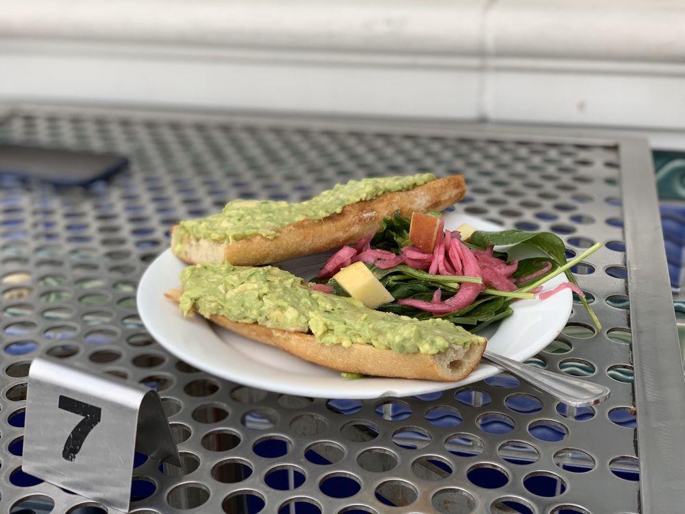 Avocado Toast · Lemony, crushed avocado on toasted Companion Bakeshop bread with dressed baby spinach, pickled red onions, toasted seeds. Served with a pickled carrot. 