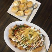 Dahi Puri · 7 puffed fried puris stuffed with potatoes, chickpeas, tamarind and green chutney, and toppe...