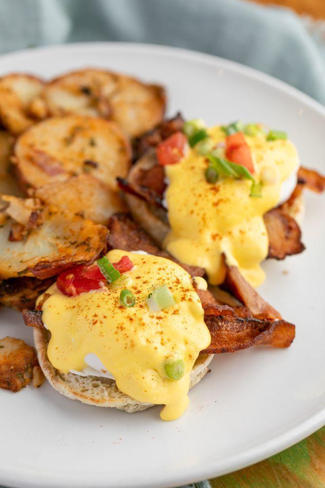Eggs Benedict · 2 poached eggs on a toasted English muffin, hollandaise sauce and choice of one of the following: spinach, real, or mock turkey, real, or mock bacon, real ham or avocado. Served with potatoes.