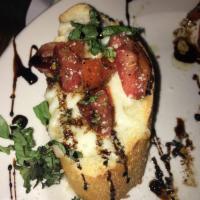 Bruschetta · Garlic bread topped with tomato, Italian herbs, mozzarella and a balsamic reduction