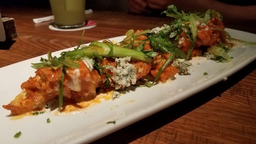 Spicy Buffalo Cauliflower · Fresh cauliflower florets buttermilk-battered and lightly fried, then tossed in housemade Sriracha Buffalo sauce and topped with a salad of celery, cilantro, scallions, and Gorgonzola. Vegetarian.