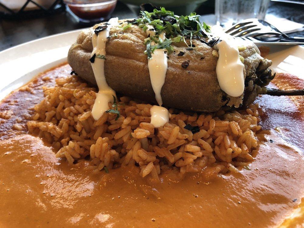 Chile Relleno · Carnitas, cheese, onion and peppers served over guajillo rice. Topped with crema, pasilla chips, suiza and ranchera sauce.