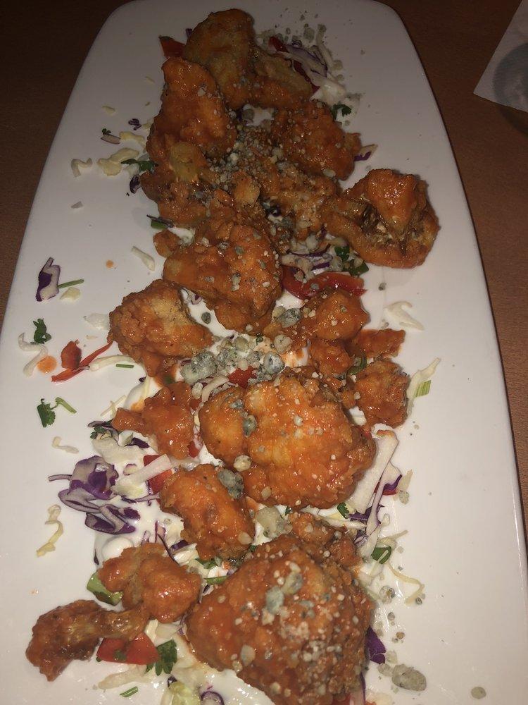 Buffalo Cauliflower · Lightly battered and fried cauliflower florets tossed in our buffalo sauce on a bed of bleu cheese dressing and crunchy cabbage. Topped with crumbled bleu cheese and freshly sliced scallions. Vegetarian and spicy.