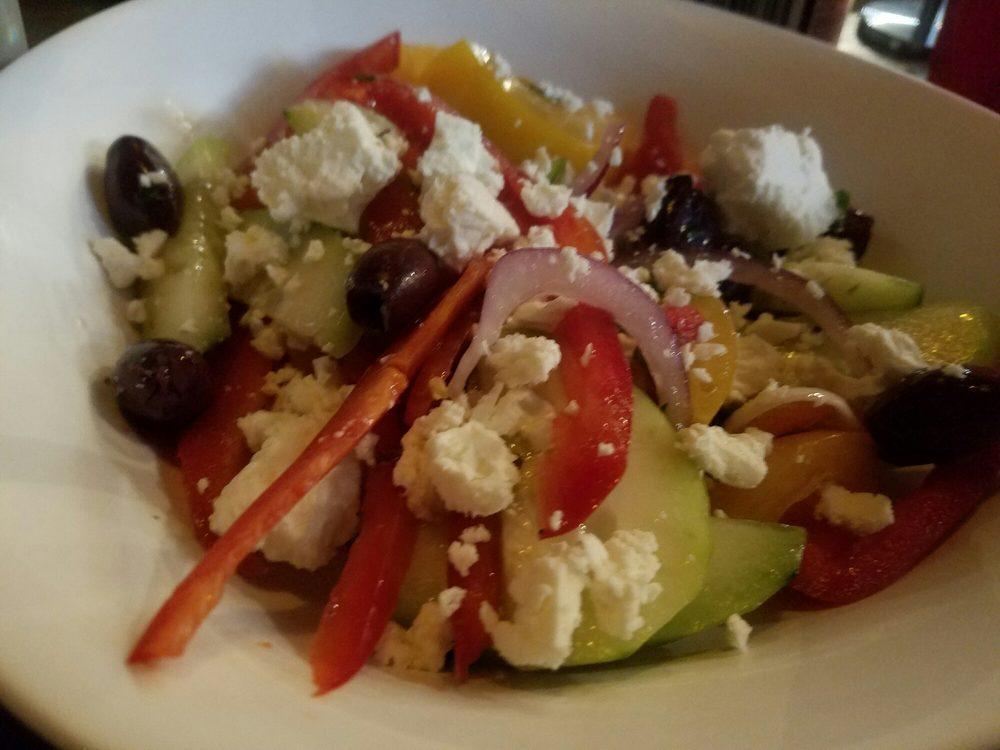 Village Salad · Traditional Greek salad with Roma tomatoes, cucumbers, red onions, bell peppers, Kalamata olives, capote capers, tossed in house-made Greek vinaigrette, topped with sliced feta cheese. Vegetarian. Gluten free.