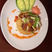 Crispy Chicken Over Rice · Breaded chicken tenders with sweet chili sauce served with sliced cucumber and ginger rice.