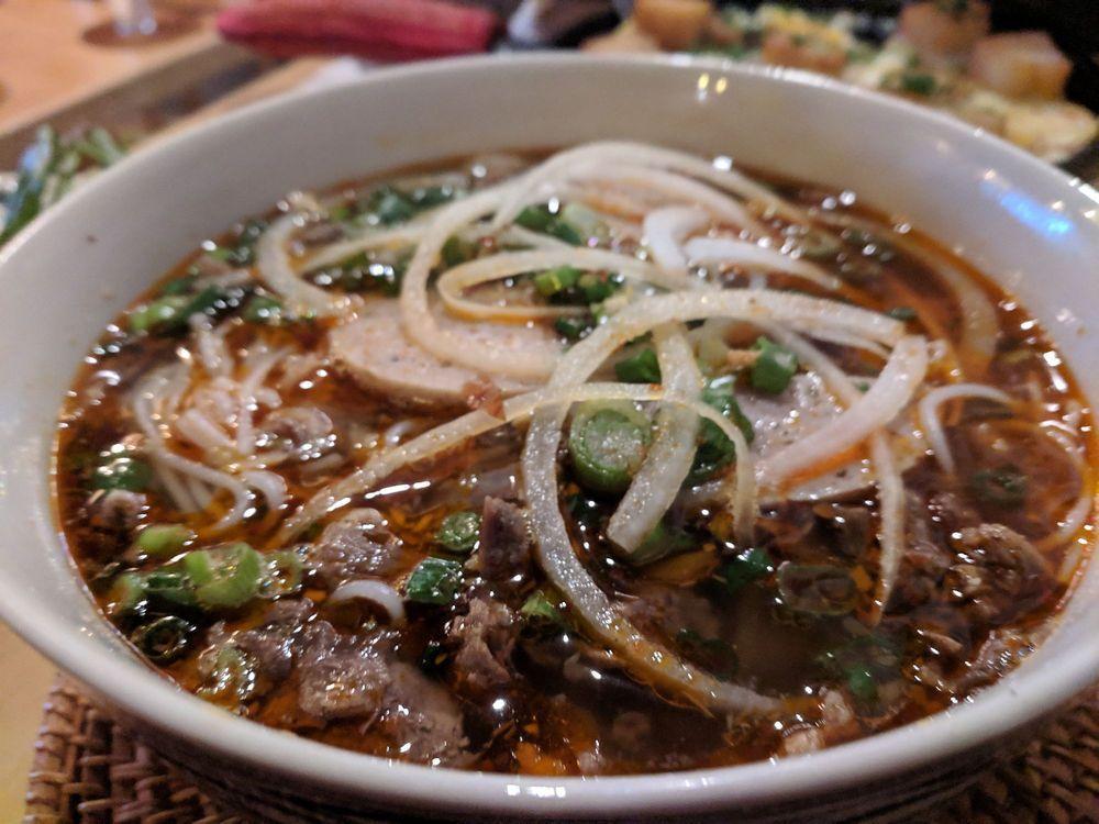 Bun Bo Hue · Spicy broth made from pork neck bones and oxtails, spiced up with garlic, shallot, lemongrass, and chili paste, topped with slices of beef shank and Vietnamese cured pork roll served with jumbo size vermicelli or pho noodle.