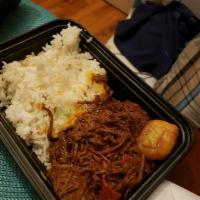 Ropa Vieja · Shredded beef skirt steak with peppers & onions in red sauce served with white rice, black b...