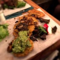 Patacones · Fried green plantain topped with mushroom duxelle sauce, roasted pork & guacamole.