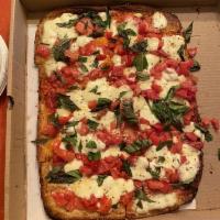Caprese Pizza · Fresh garlic and olive oil, fresh mozzarella and diced tomatoes on a grandma style pizza.