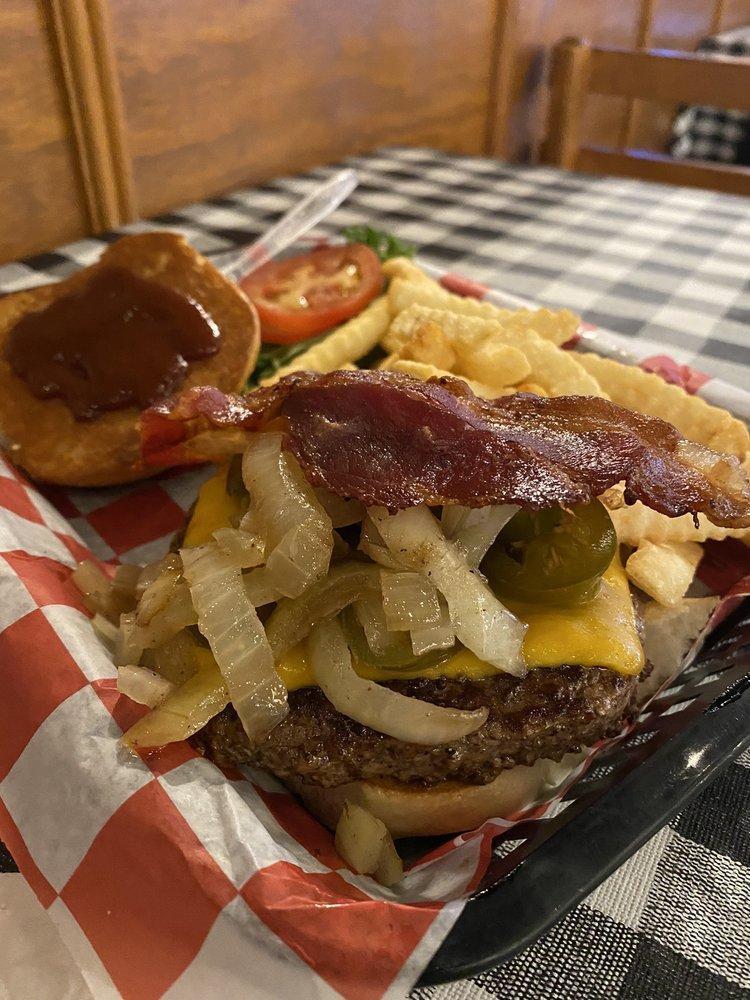 The Q Burger · 1/2 lb. burger, crispy bacon, grilled onions, melted Cheddar, and topped off with BBQ sauce. Made with 100% fresh ground beef. Served on unique bun and with a side of pinto beans.