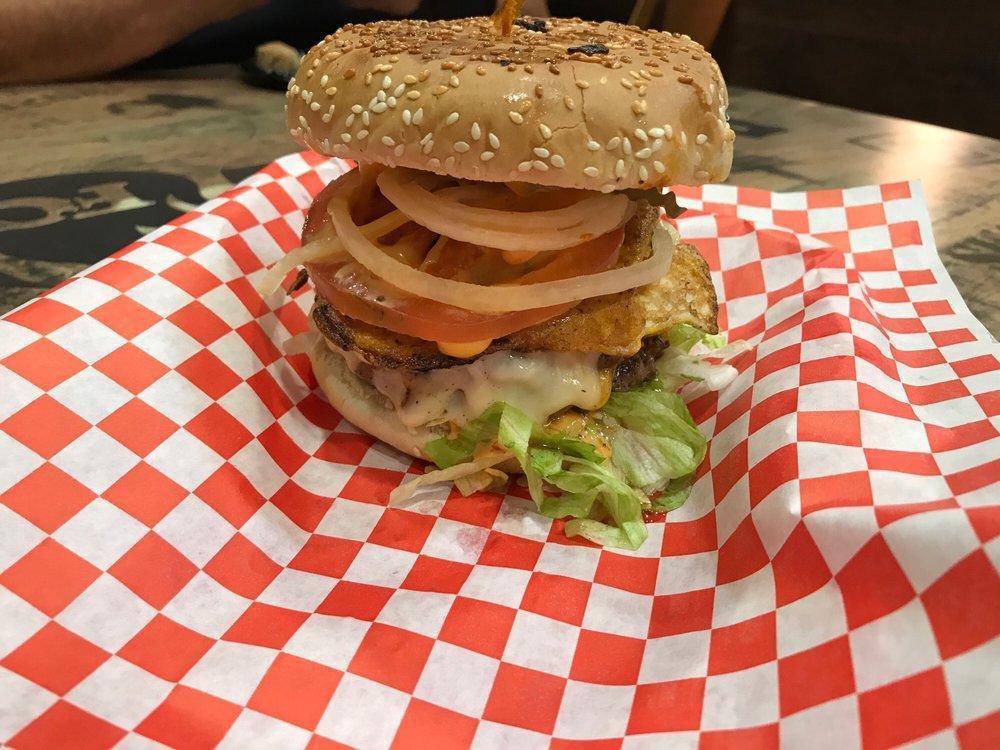 Badmash Burger · Lettuce, badmash sauce, double patty, egg, bacon, Swiss, cheddar cheese, mayo, pickles, onion and tomatoes.