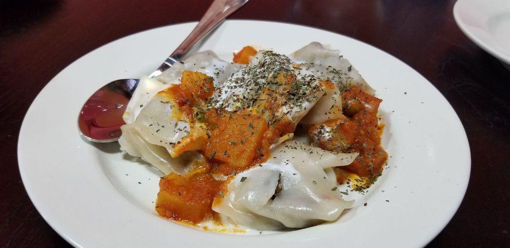 Mantu · Steamed dumplings filled with ground beef and onions, topped with lentils, and mint garlic yogurt sauce.