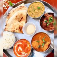 Vegetable Thali · A plate with 7 small pots, 4 vegetables, rice, raita, dessert and naan or chappati.