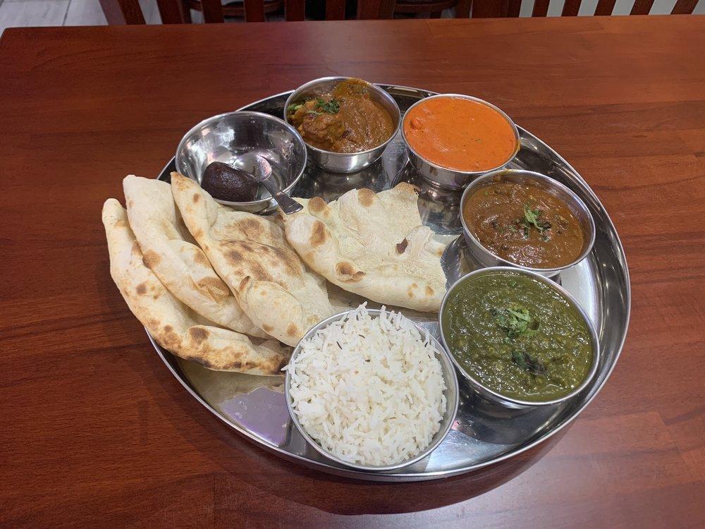 Non Vegetable Thali · A plate with 7 small pots, curry, lamb curry, vegetables, rice, raia, deesert and naan or chappati.