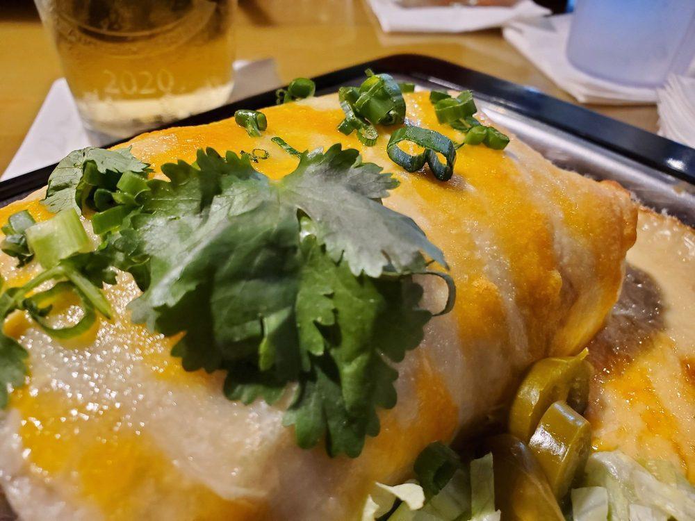 Drunken Wet Burrito · Our wet burrito smothered in beer cheese queso. Black beans, brown rice, roasted red peppers, shredded cheddar jack cheese, tomatoes and lettuce all wrapped in a flour tortilla, smothered in beer cheese queso, then baked to perfection and served with sour cream, pickled jalapenos, green onions, lettuce and fresh cilantro. Vegetarian. 