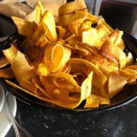 Mariquitas · Plantain chips topped with garlic sauce.