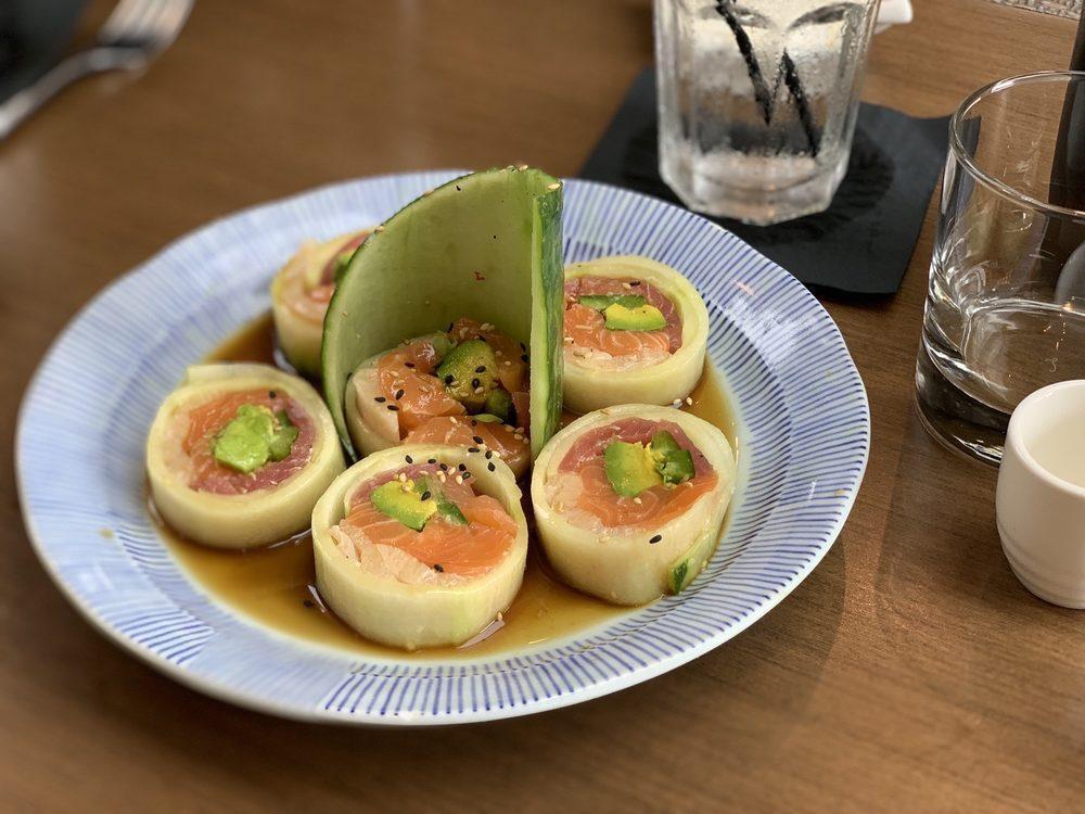 Cherry Blossom Roll · Fresh salmon, tuna, yellowtail, avocado, spicy sprouts and jalapeno rolled in a thin cucumber sheet served on a bed of ponzu sauce and topped with sesame seeds.