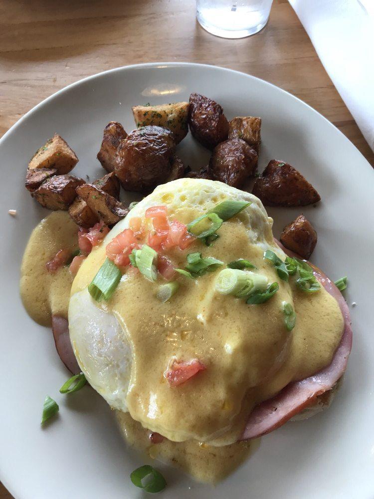 Eggs Benedict · 2 halves of a honey-wheat English muffin topped with over easy eggs, sliced ham, diced tomato, sliced green onions and Hollandaise sauce.  Served with a side of seasoned breakfast potatoes.