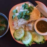 Khao Mun Gai · Hainanese style chicken over steamed garlic-ginger-oil jasmine rice. Served with cucumber, g...