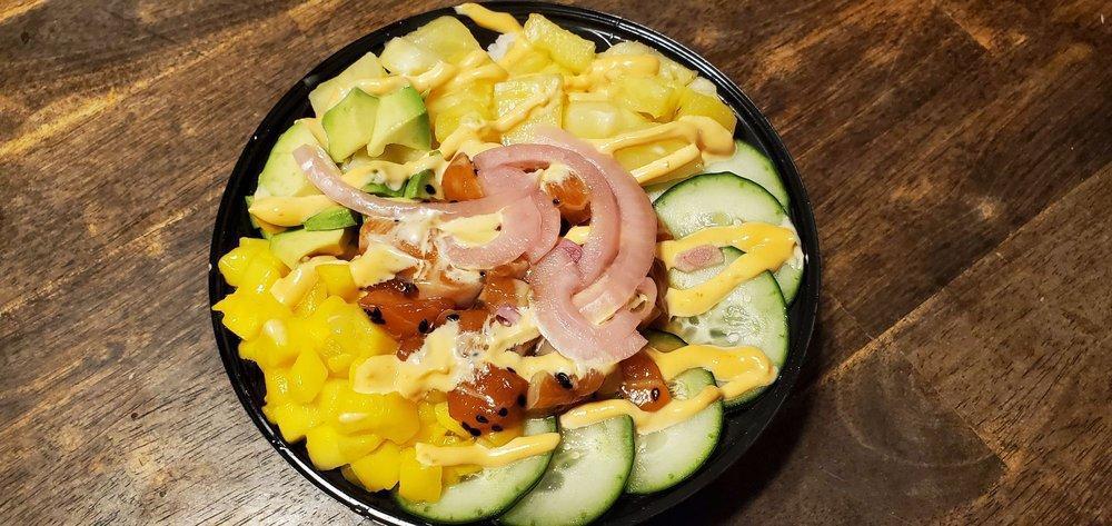 Poke Bowl · A bowl of sushi rice, raw tuna or salmon, (soy and sesame oil), pineapple, mango, cucumber, avocado , pickle, red onion, black sesame seeds, ginger, garlic and spicy Spanish mayo.