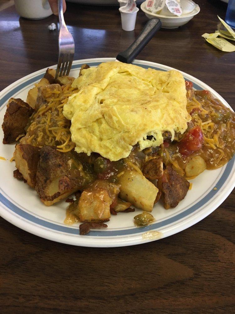 Train Wreck · 1/2lb hamburger patty on top of home fries, smothered in red or green chili, cheese and topped with 2 eggs any style.