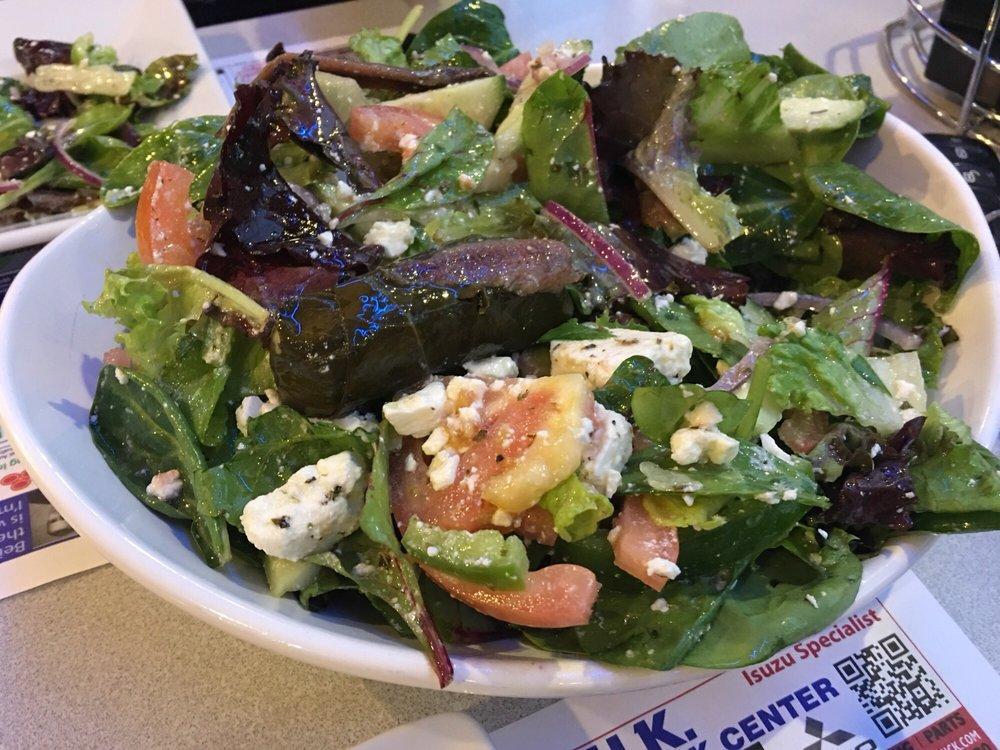 Greek Salad · Mixed greens, tomatoes, onions, peppers, Kalamata olives, feta cheese, anchovies, cucumbers, stuffed grape leaves and Greek vinaigrette dressing served with pita bread.