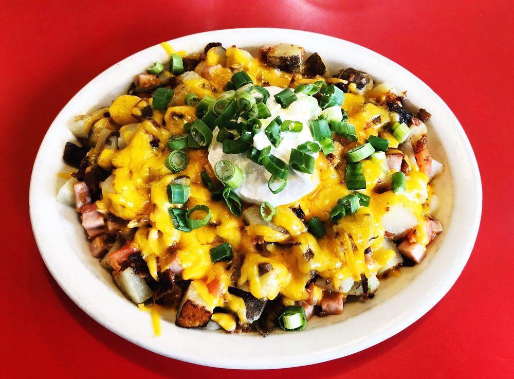 Montana · Big mountain of our grilled potatoes with green peppers and onions, tomato, diced bacon, ham, and covered with Wisconsin cheddar cheese. Then topped with sour cream and green onions.