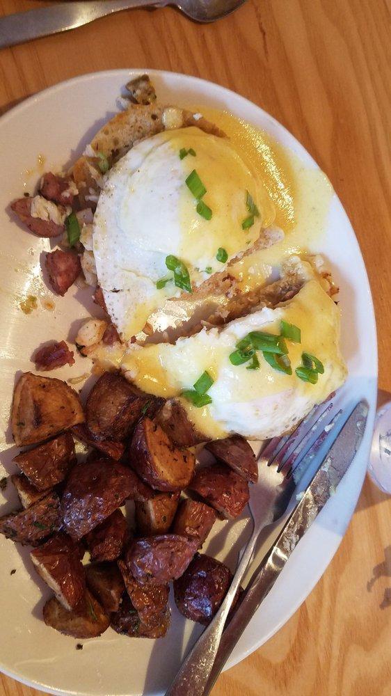 Eggs Benedict · Two halves of a honey-wheat English muffin topped with over easy eggs, sliced ham, diced tomato, sliced green onions and hollandaise sauce. Served with a side of seasoned breakfast potatoes.