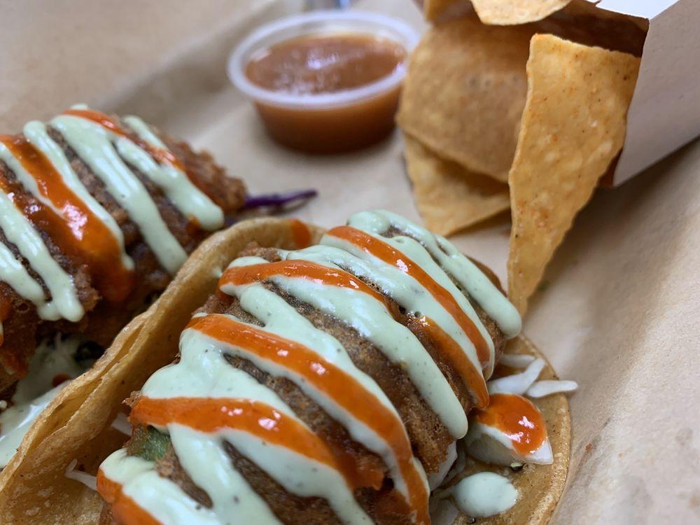 Beer Battered Avocado Tacos · 2 street taco sized tacos per order. Beer battered avocado on a bed of purple and green cabbage, topped with a creamy cilantro pepita dressing and Sriracha. Served with chips. Gluten free style available upon request.