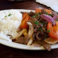 Lomo Saltado · Classic Peruvian dish. Sautéed marinated beef with red onions, tomatoes, soy sauce, and spic...