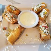 Taquitos · Crispy flour tortillas with choice of chicken or steak topped with sour cream, queso fresco ...