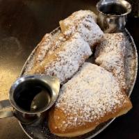 Beignets · Lightly fried dough rolled in a cinnamon-sugar glaze and topped with powdered sugar.