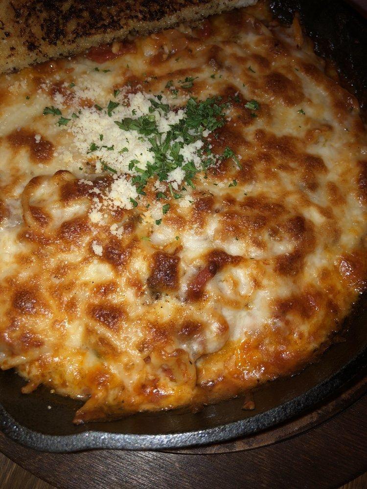 Cast Iron Baked Spaghetti · Our famous homemade spaghetti baked in a cast iron skillet smothered in our 3-cheese blend. Served with garlic bread.