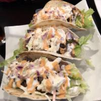 Korean Tacos · Spicy chicken or marinated ribeye over three warm flour tortillas filled with crisp lettuce ...