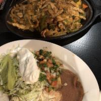 Fajitas · Chicken or steak strips grilled with bell peppers, onions and tomatoes. Served with beans gu...