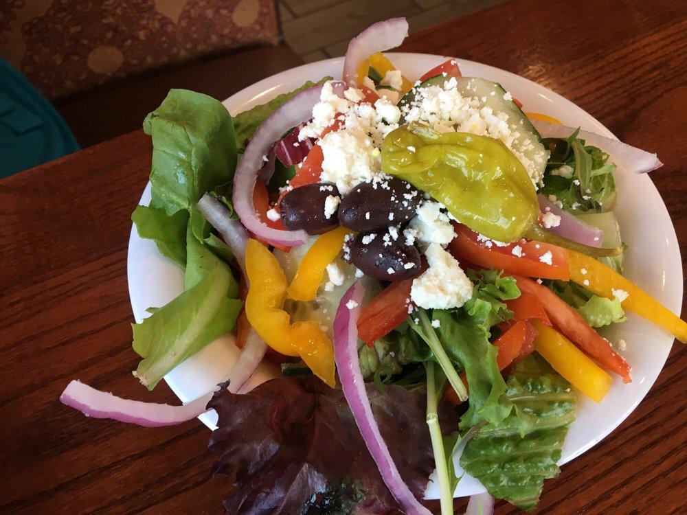 Greek Salad · Romaine lettuce, red onions, tomato, cucumber, peppers, Kalamata olives, feta cheese and pepperoncini. Vegetarian and gluten free.