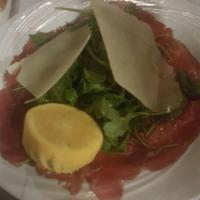 Beef Carpaccio · Thin slices of raw beef, arugula and Parmesan cheese seasoned with olive oil and lemon juice.