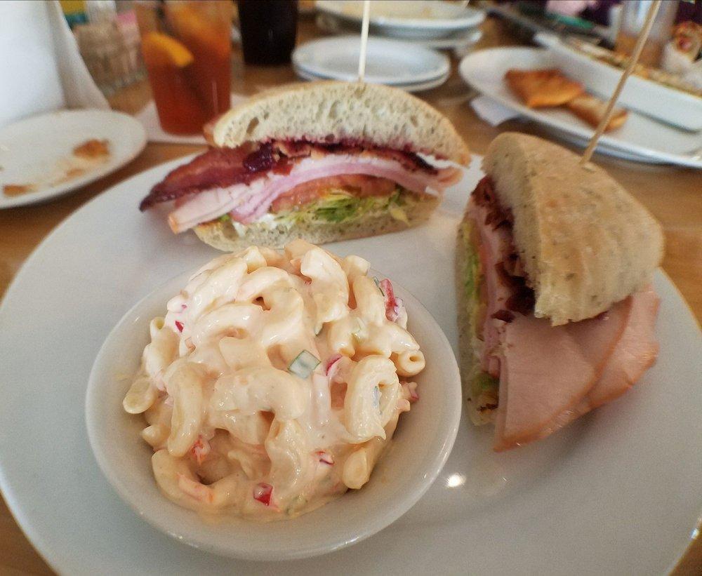 Tourist Tan · Applewood smoked bacon, smoked turkey, black forest ham. Topped with cranberry relish, rosemary basil mayo, lettuce & tomato on a grilled herb focaccia bread.