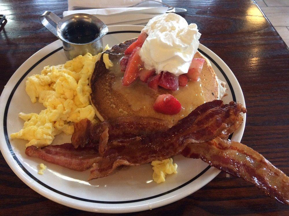 Buttermilk Pancakes with Eggs and Bacon · Four fluffy buttermilk pancakes with butter and vanilla maple syrup. Served with a side of bacon and scrambled eggs.