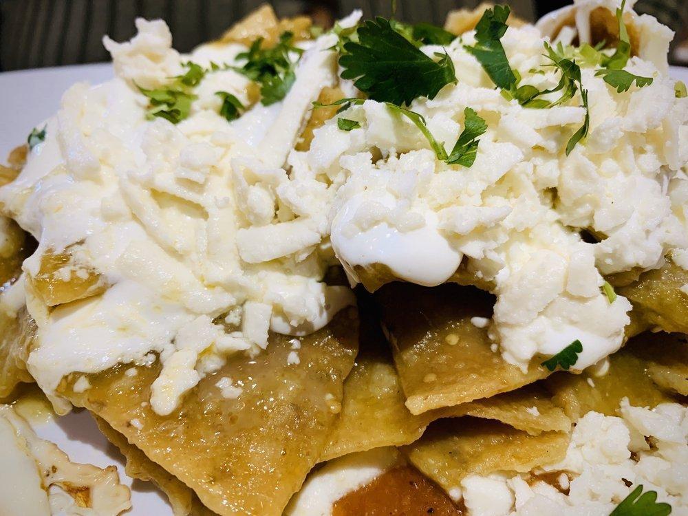 Chilaquiles Verdes · Fried tortilla chips bathed in our green salsa, topped with Mexican sour cream, queso fresco, red onion, cilantro, served with homemade re-fried beans and 2 eggs any style.